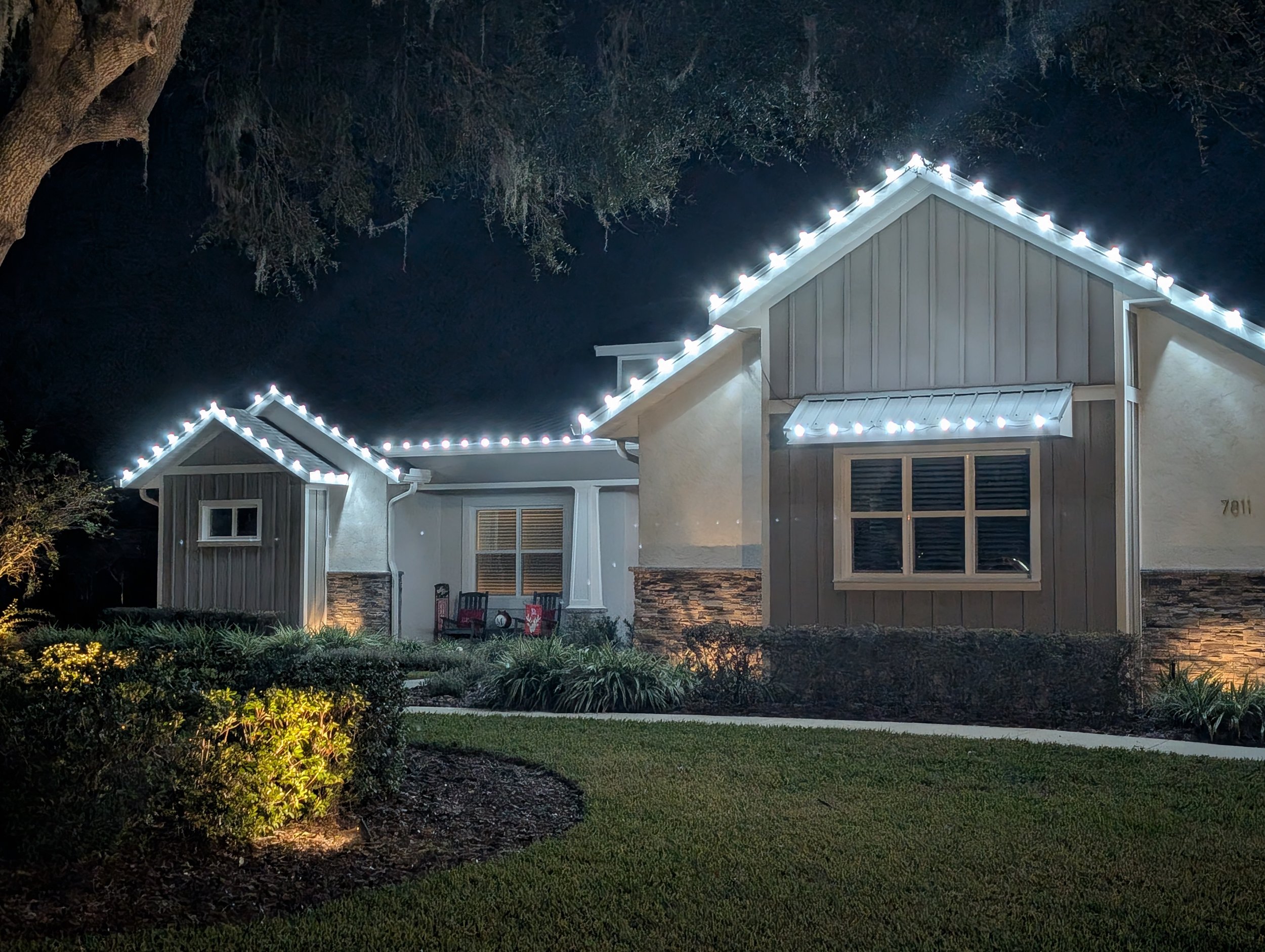 Light stucco home outlined in white Christmas lights