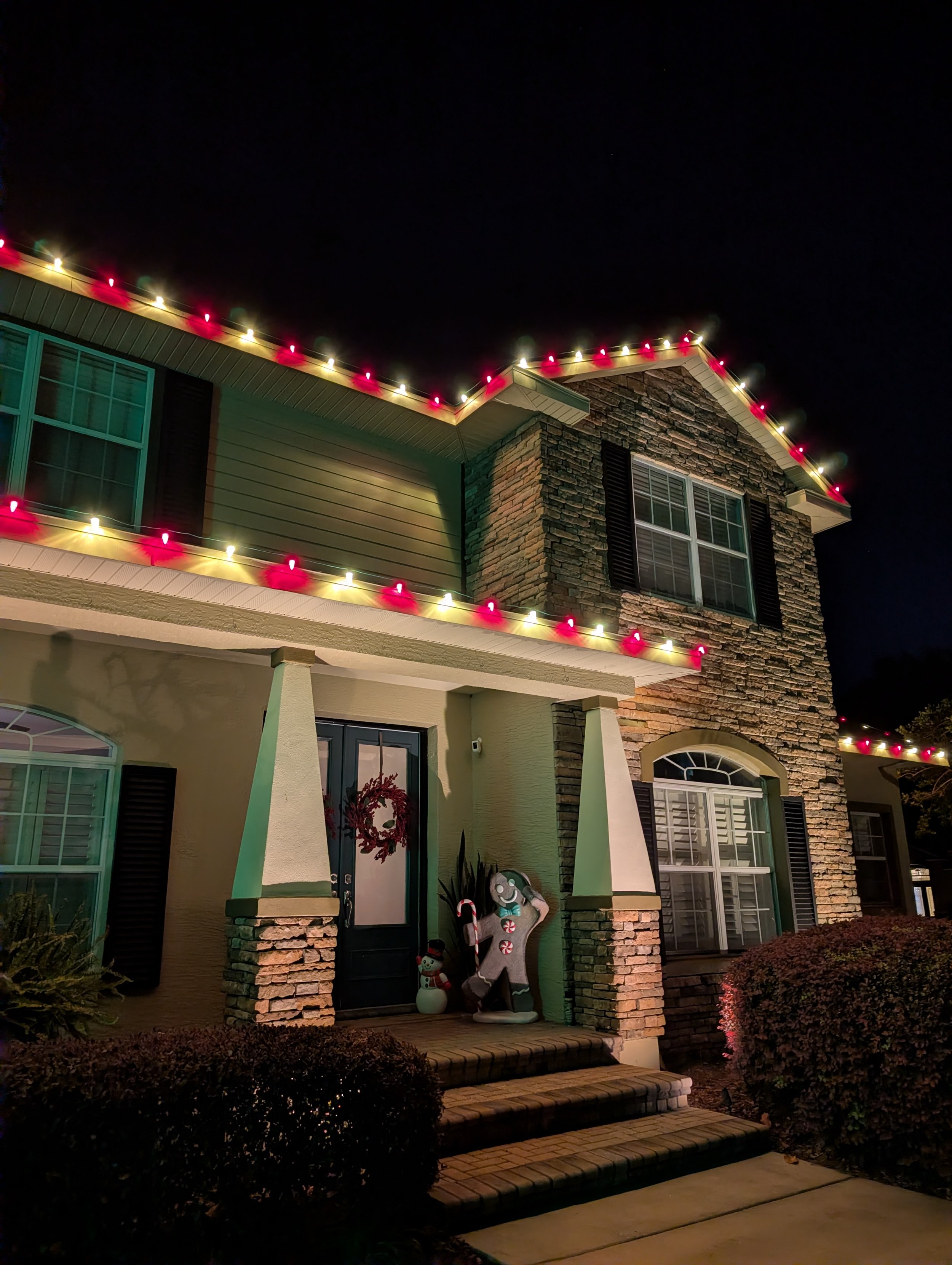Two-story home with alternating red and white Christmas lights